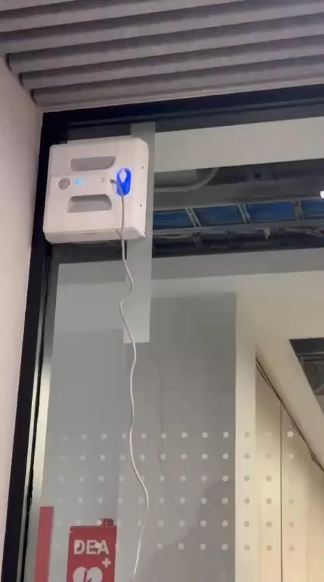 Robot limpiador de ventanas adherido a una mampara de vidrio